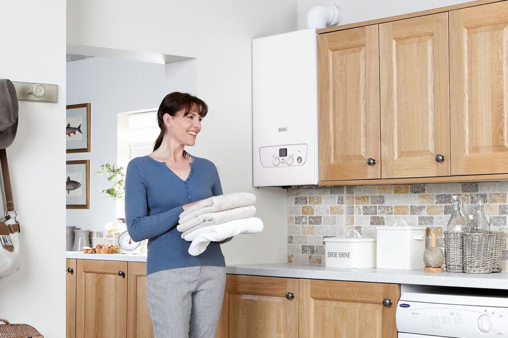 Female carrying clean folded washing through kitchen with Baxi boiler in background